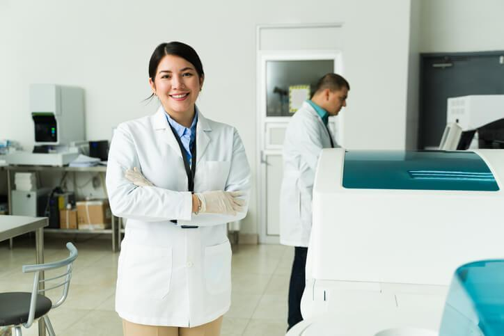A smiling female pharmacy technician in a laboratory after completing her pharmacy technician training
