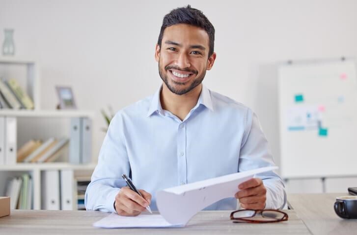 Male paralegal writing on a notepad in an office after completing his paralegal program